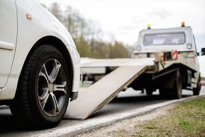 A tow truck is towing a car to car donation center